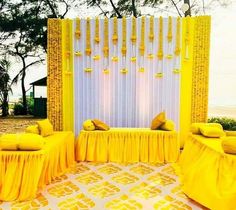 a yellow and white stage set up for a wedding ceremony with pillows on the floor