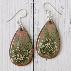 the earrings are made out of wood and decorated with flowers, leaves, and berries