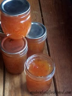 four jars filled with orange liquid sitting on top of a wooden table