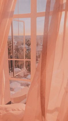 an open window with sheer curtains and a view of the city from it's bedroom