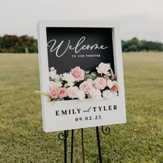 a welcome sign with flowers on it in the grass