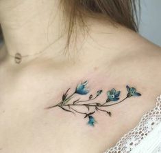 a woman's back shoulder with blue flowers on her left arm and the upper part of her chest