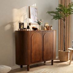 a living room with a large wooden cabinet next to a potted plant in the corner