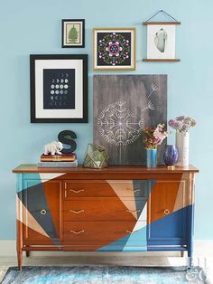 a room with blue walls and pictures on the wall, including an art piece above a dresser