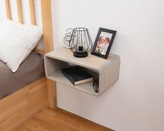 a small shelf on the wall next to a bed with a framed photo and books