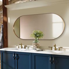 a bathroom vanity with two sinks and a large round mirror above it, in front of a brick wall