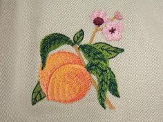 an embroidered peach with leaves and flowers on it