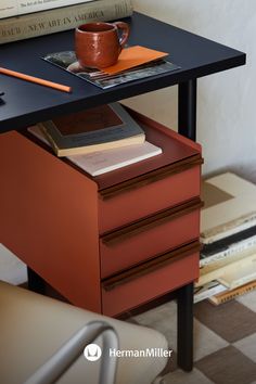 a table with two drawers and a coffee cup on it next to a stack of books