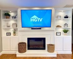 a television mounted above a fireplace in a living room with white built - in shelves