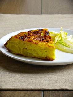 a piece of quiche on a white plate with lettuce