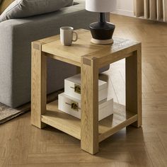 a coffee table with some books and a cup on it in front of a couch