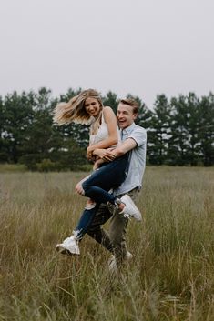 a man carrying a woman on his back in the middle of a field with tall grass