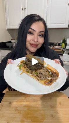 a woman holding a plate with a sandwich on it in front of her face and smiling at the camera