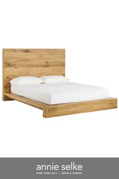 the bed frame is made from wood and has white sheets on it, along with two pillows