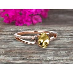 a yellow diamond ring on top of a wooden table with pink flowers in the background