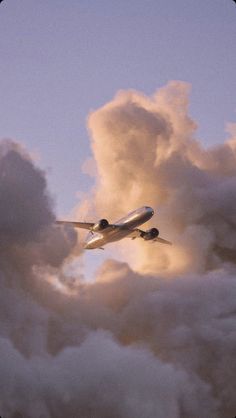 an airplane is flying through the clouds in the evening sky with it's landing gear down