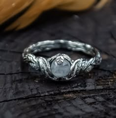 a silver ring with a stone in the center on top of a piece of wood