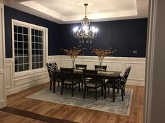 a dining room with blue walls and white trim around the chandelier is shown