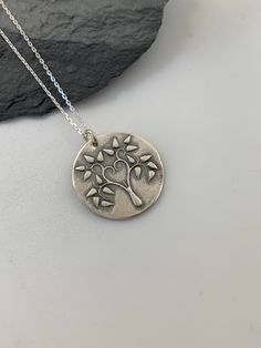 This unique Tree of Life handmade embossed round pendant has been entirely handmade using .999 fine silver. It has been cut from fine silver precious metal clay, textured, fired and oxidized. The pendant hangs from a sterling silver diamond cut cable chain. This fine silver pendant features an embossed Tree of Life image on one side of the pendant and is reversible to a tiny leaves embossed pattern on the reverse side. Pendant size: approximately 3/4 x 3/4 inches Chain length: adjustable at 16 a Moon Necklace Silver, Silver Bar Necklace, Metal Clay Jewelry, Layered Necklaces Silver, Pendant Necklace Silver, Unique Trees, Charm Necklace Silver, Silver Tree, Sterling Silver Chain Necklace