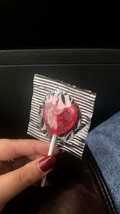 a woman's hand holding a lollipop heart shaped lollipop on a stick