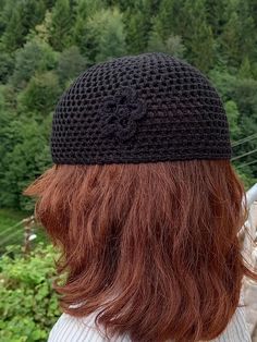 a woman with long red hair wearing a black crochet hat on top of her head