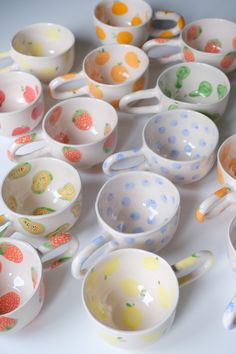 there are many bowls and spoons that have fruit designs on them, all in different colors