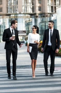 three business people are walking across the street