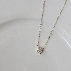 a white plate with a silver necklace and a small diamond pendant on it's chain