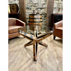 a glass table sitting on top of a wooden floor next to two brown leather chairs