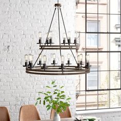 a chandelier hanging over a dining room table in front of a brick wall