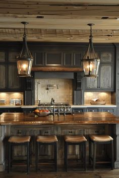 a kitchen island with stools and lights hanging from it's ceiling over the counter