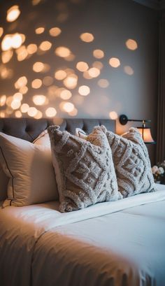 a bed that has some pillows on top of it and lights in the wall behind it