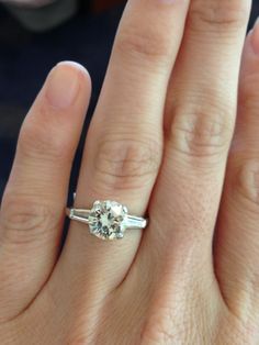 a woman's hand with a diamond ring on top of her finger and an engagement band