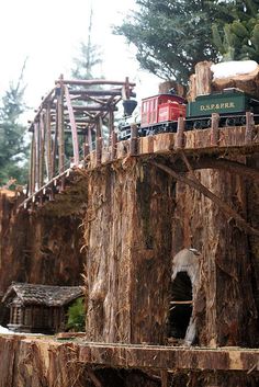 a model train set on top of a tree stump structure with trees in the background