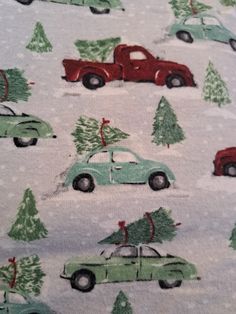 the fabric has cars with trees on them and snowflakes in the back ground