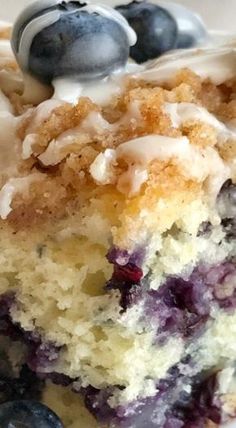 a close up of a piece of cake with blueberries and cream frosting on it