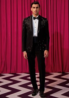 Step into elegance with our Black Textured Tuxedo Set. Crafted from luxurious textured suiting, this set features an elegant black blazer embellished with intricate linear embroidery. Paired with an embellished bowtie, sash, pintuck shirt, and pants, it's the ideal choice for cocktails or wedding receptions. Make a statement and exude sophistication in this stunning tuxedo set. Components : 5 (Blazer, Shirt, Bowtie, Sash and Pants) Composition : Textured Suiting Care: Dry Clean Only and Vacuum Storage This product can be customized for sleeves, length of blouse and neckline Delivery : 4-6 weeks as the product is hand crafted. Check Size Guide or choose MySize for free customisation (All Sizes above XL can be made at 15% additional cost) For more information and sizes please contact fabilic Luxury Embellished Blazer With Notch Lapel, Luxury Tailored Embroidered Suits, Tailored Elegant Blazer For Gala, Elegant Tailored Blazer For Gala, Tailored Elegant Tuxedo For Gala, Embellished Notch Lapel Suits For Semi-formal Occasions, Tailored Embellished Sets For Party, Elegant Evening Sets For Party Season, Elegant Tuxedo For Gala