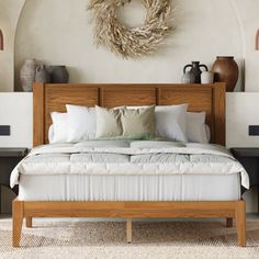 a bed with white sheets and pillows in a room next to two vases on the wall