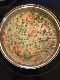 a pot filled with peas and carrots on top of a stove