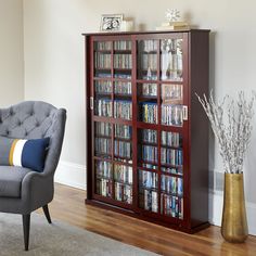 a living room filled with furniture and a tall book case next to a chair in front of a window