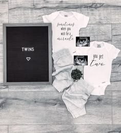 two onesuits and a chalkboard with the words twins next to it on a wooden floor