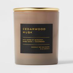 cedarwood musk scented candle in glass jar with gold lid and black label on white background