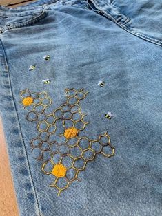 a pair of jeans with embroidered bees on them