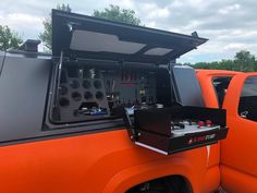 an orange truck with its doors open and electronics in the back compartment, on display