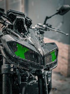 a close up of a motorcycle with green arrows on the front and back lights, in the rain