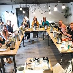 a group of people sitting at long tables with food in front of them and smiling