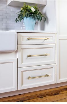 a white kitchen with gold handles and drawers