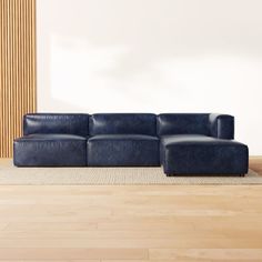 a blue leather couch sitting on top of a wooden floor next to a white wall