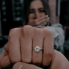 a woman holding her hand up to the camera with a diamond ring on it's finger