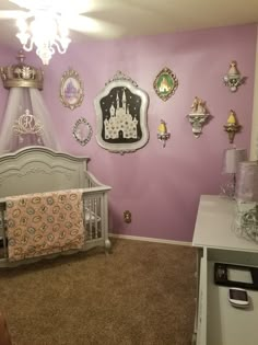 a baby's room decorated in purple and gold with princess decorations on the wall